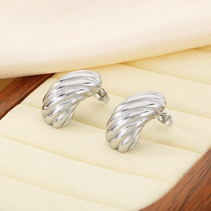 Gros plan de boucles d'oreilles créoles en C argentées dans un coffret à bijoux beige