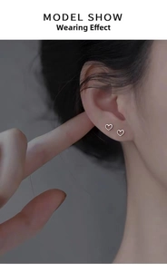 Orecchini a perno minimalisti a cuore cavo in argento indossati per un look quotidiano