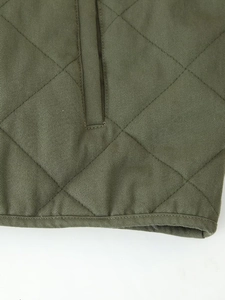 Close-up of diamond quilted army green jacket fabric with detailed stitching and binding