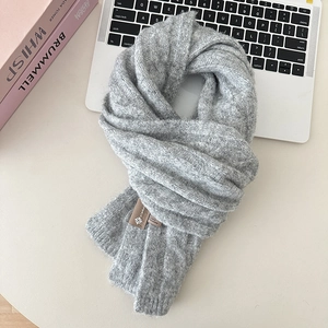 Close-up of soft grey knit wool scarf with a high-quality cable-knit texture and pinda label