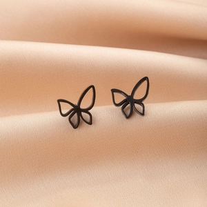 Detail shot of black hollow butterfly stud earrings on champagne silk fabric surface