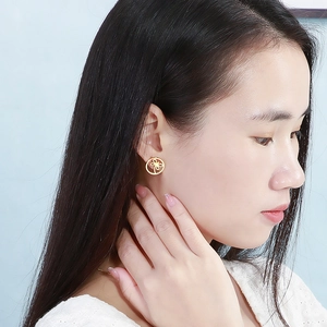 Detailed close-up of a model wearing a gold hollow flower round earring