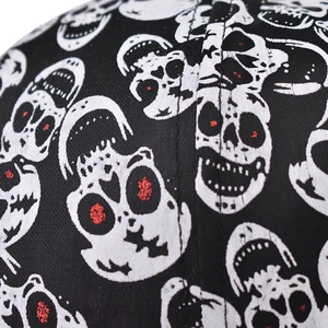 Detail von schwarzem Canvas-Stoff mit weißem Totenkopf-Print und roten Pailletten