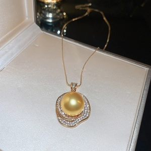 Gros plan détaillé d'un pendentif perle dorée avec cristaux dans son coffret à bijoux