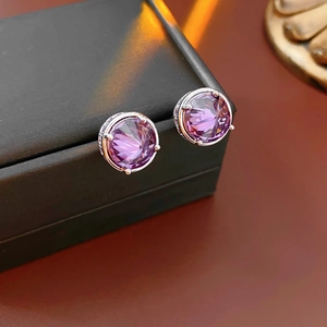 Macro shot of 18k gold plated silver earrings with purple zircon and sparkling crystals