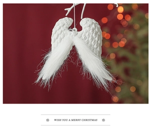 Close-up of white feather angel wings Christmas ornament with glitter on a snowy branch