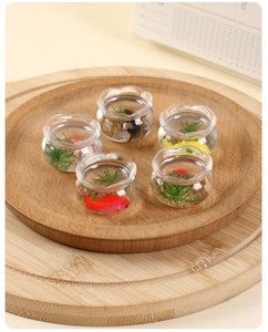 Vue de dessus de cinq mini bocaux à poissons colorés sur un plateau en bois