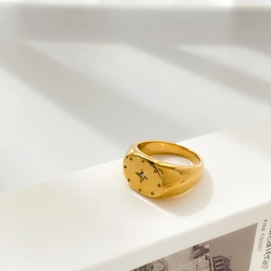 Close-up of golden signet ring featuring a starburst engraving and sparkling zircon