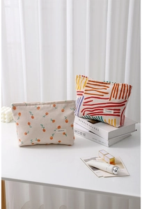 Detail of floral and abstract corduroy makeup bags with gold zippers and brand labels