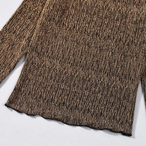 Détail du tricot bronze métallique montrant une texture scintillante et un bord ondulé