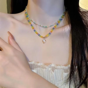 Close-up of a double-layered rainbow beaded necklace with heart pendant on a model