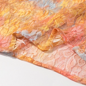 Detail of floral lace mesh fabric with colorful orange and pink prints and hemmed edges