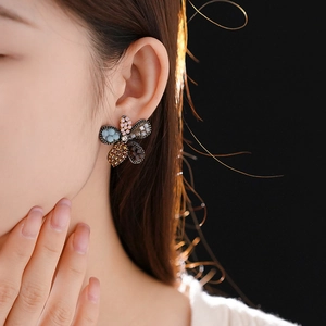 Close-up of a flower-shaped earring with colorful rhinestones worn by a model