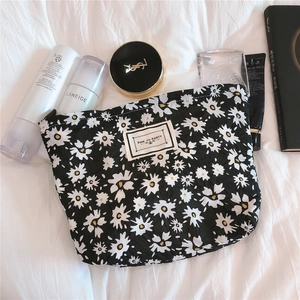 Detail of black floral daisy makeup bag with Time to Party label on white fabric