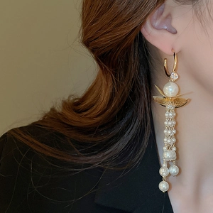 Detail of long pearl tassel earring with gold lotus leaf and zircon on a model