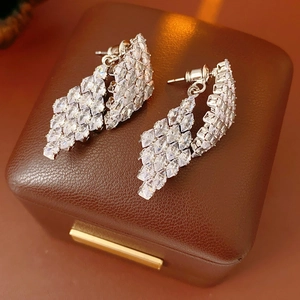Macro shot of silver diamond-shaped drop earrings with cubic zirconia on a leather box