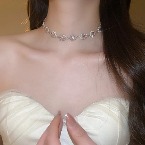 Close-up of pink heart-shaped crystal necklace with silver setting on a model