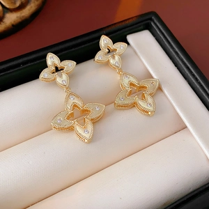 Macro shot of gold-plated clover earrings with white rhinestones and beaded edges