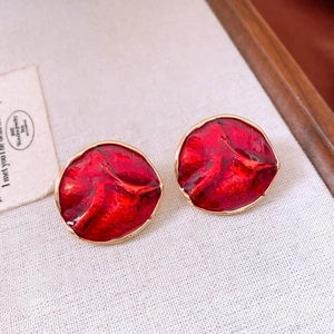 Detail of red resin round pendant earrings with gold metal frame on a wooden tray