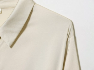 Vue détaillée du col de chemise en satin crème et texture d'épaule lisse