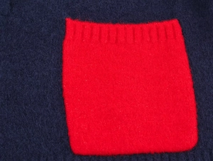 Macro view of navy wool knit cardigan featuring a contrasting red ribbed pocket detail