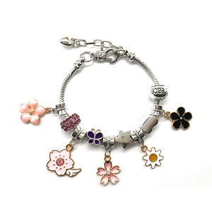 Detail of silver alloy charm bracelet with peace engraving and floral bead charms