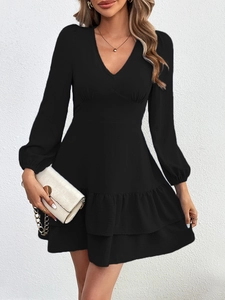 Détail de mini robe noire avec volants étagés, col en V et manches longues élégantes
