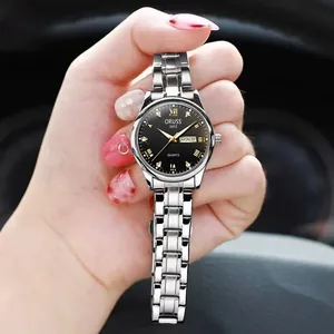 Macro detail of ORUSS quartz watch showing black dial with day-date window and steel band