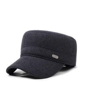 Detail of dark grey winter flat cap with earflaps and metal logo plaque on thick fabric