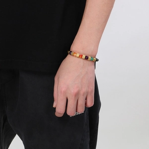 Bracciale di perline colorate con pietre naturali e dettagli dorati al polso di un modello