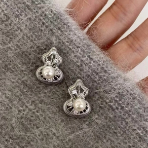 Gourd-shaped silver needle earrings with pearl and small diamonds on grey knit fabric
