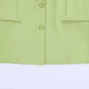 Gros plan détaillé du blazer vert clair avec doubles boutons et finitions des poches