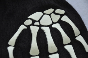 Macro shot of knitted texture and white skull bone skeleton print on fingerless gloves