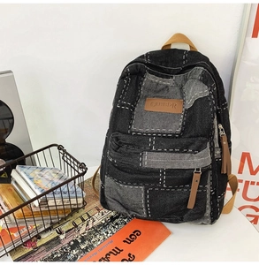 Detail view of washed black denim backpack with white stitching and leather accents