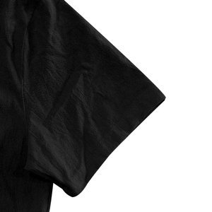 Close-up of sleeve stitching and textured linen fabric on a black short sleeve shirt