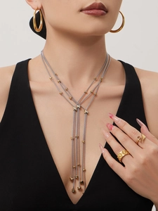 Détail d'un mannequin portant un collier à gland bicolore et des bijoux dorés chics