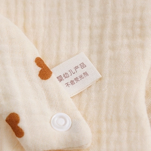 Detail of soft 6-layer cotton gauze bib with brown heart patterns and resin snap buttons