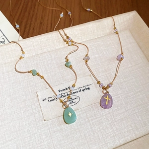 Détail de colliers en perles avec pendentif étoile verte et breloque croix violette