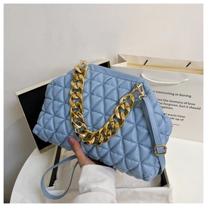 Detail of blue quilted handbag with chunky gold chain strap and matching leather shoulder strap