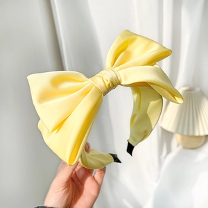 Detail of a high-quality yellow satin bow headband with smooth texture and minimalist design