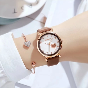 Women's quartz watch with brown leather strap and hollow heart dial design on wrist