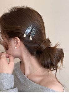 Detail of grey marble duckbill hair clips with colorful rhinestones on brown hair