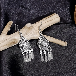 Detail shot of vintage silver earrings with metallic tassels on natural driftwood