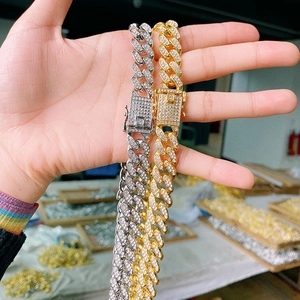 Detail of silver and gold Cuban link chains with iced-out pave crystals held by hand