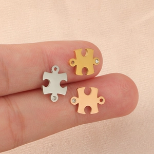 Set of three puzzle-shaped stainless steel charms in gold, silver, and rose gold with stones