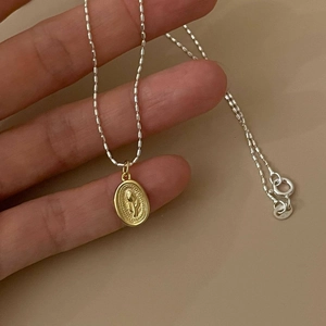 925 silver necklace with golden oval floral relief pendant held in hand for detail