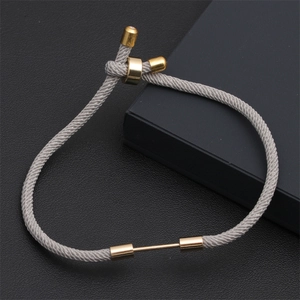 Detail of adjustable grey braided cord bracelet with polished gold-tone metal accents