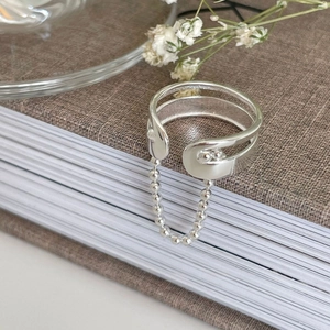 925 silver double-layered open ring with safety pin design and bead chain charm on a book