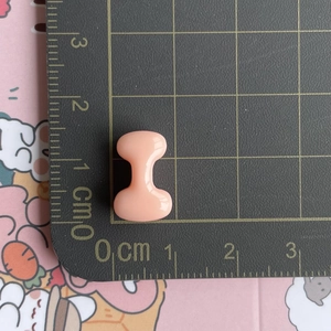 Mini pink resin alphabet accessory measured on a grid showing 1cm x 0.5cm scale size