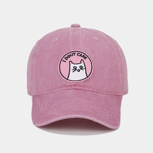 Detail of pink washed cotton baseball cap featuring embroidered cat patch and I DOUT CARE text